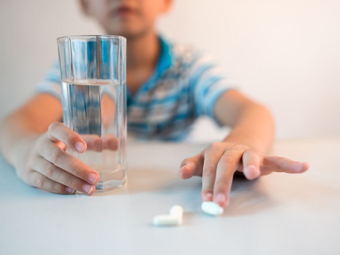 boy with cup of water and medicine in hand