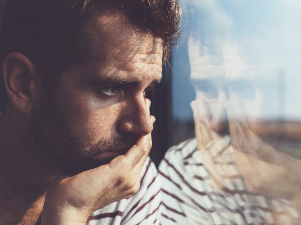 depressed young man looking out window 5htp