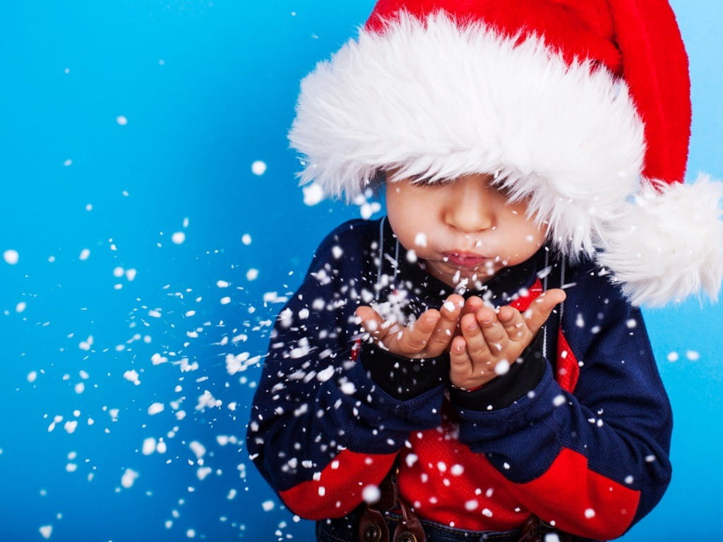 young boy blowing artificial snow out of his hands