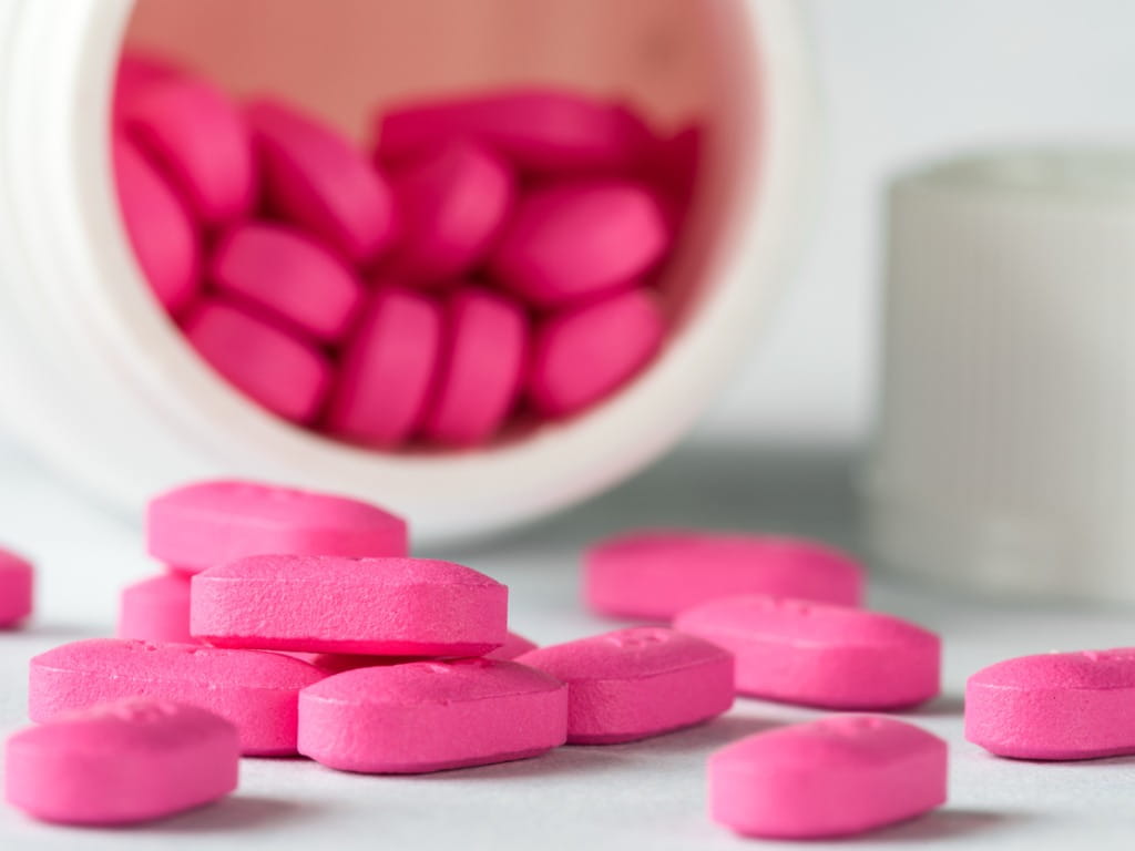 pink pills spilling out of a medicine bottle