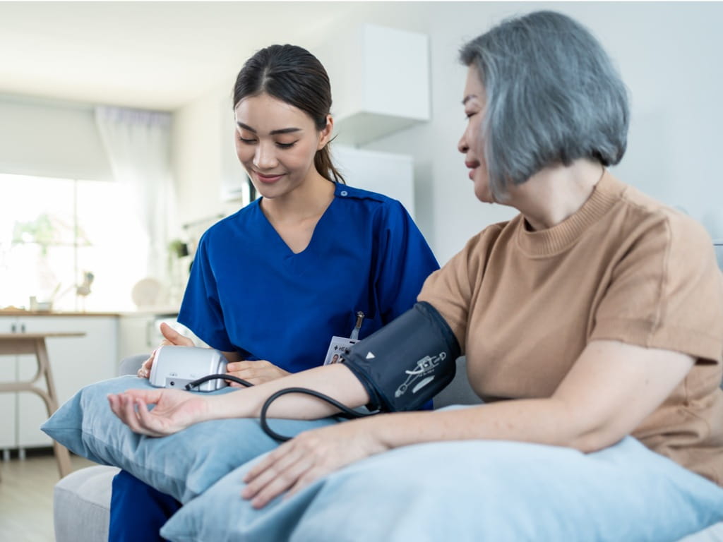 caregiver checking her patient's blood pressure