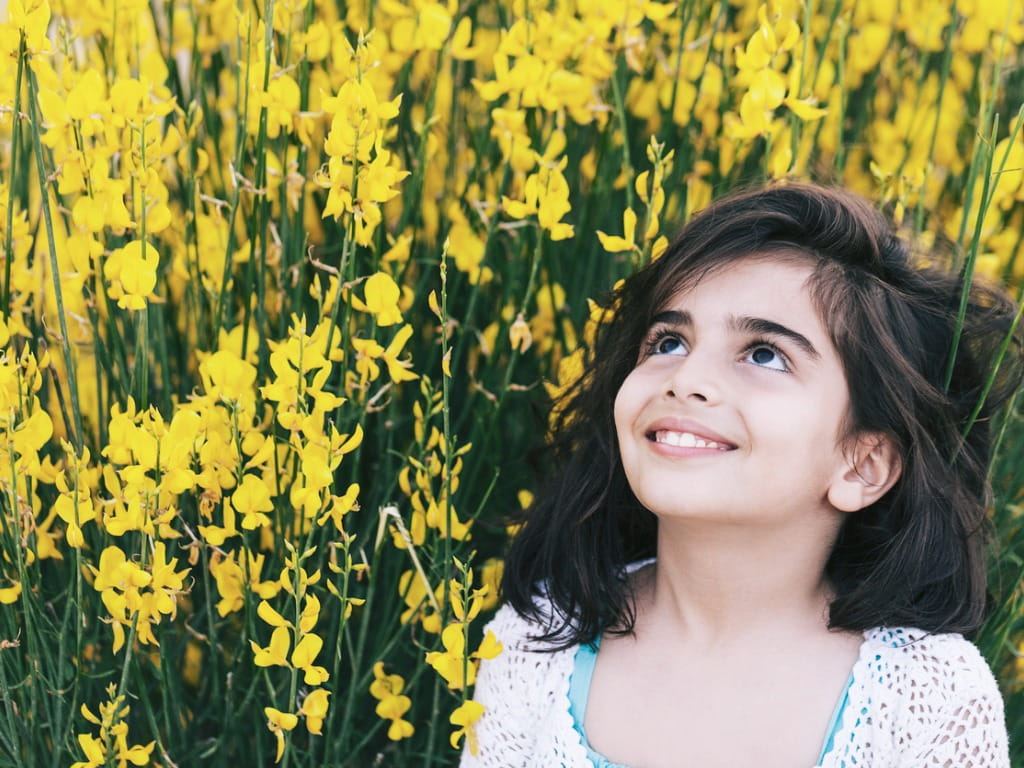 child surrounded by spanish broom flowers