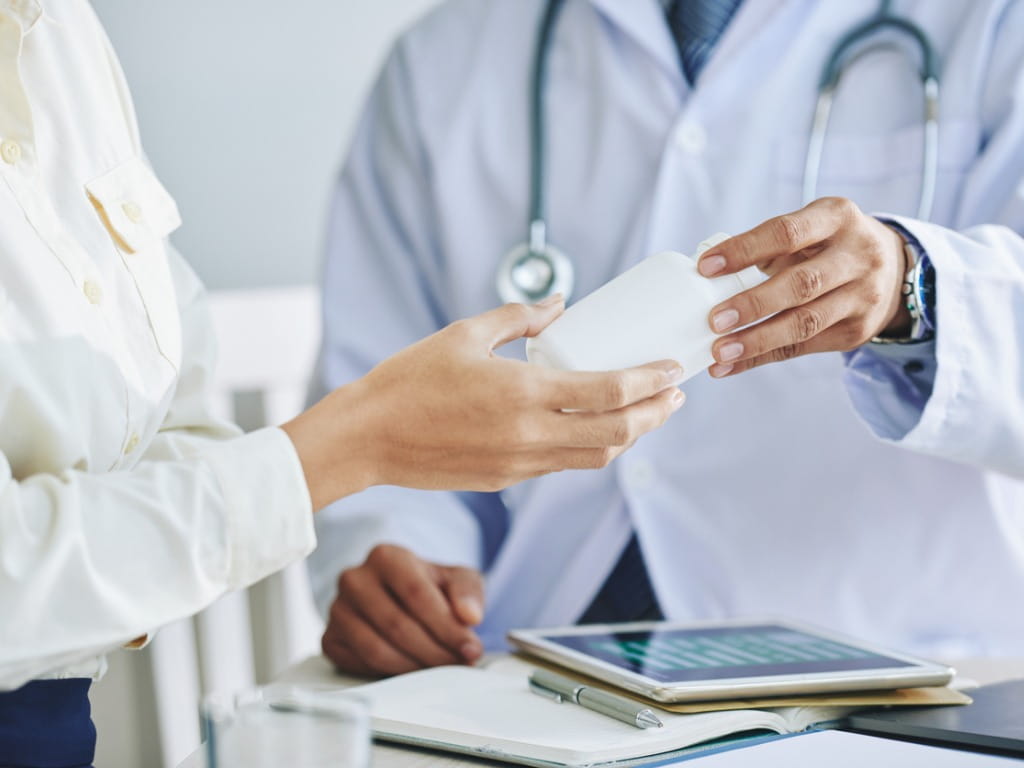 doctor handing a prescription bottle to a patient