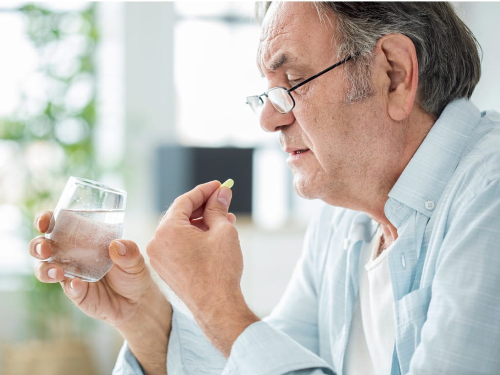 elderly man taking a pill