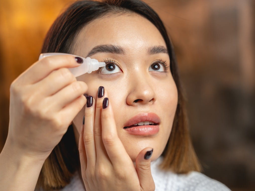 young asian woman using eye drops
