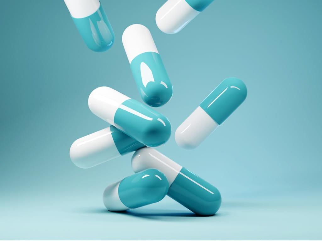 medicine capsules falling on blue background