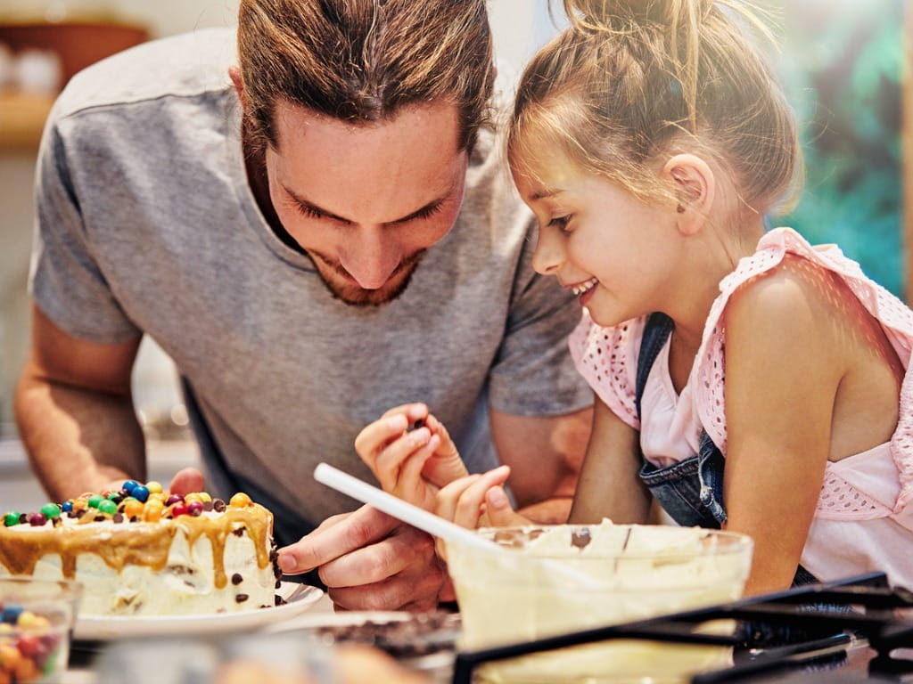 Father and daughter decorate a cake