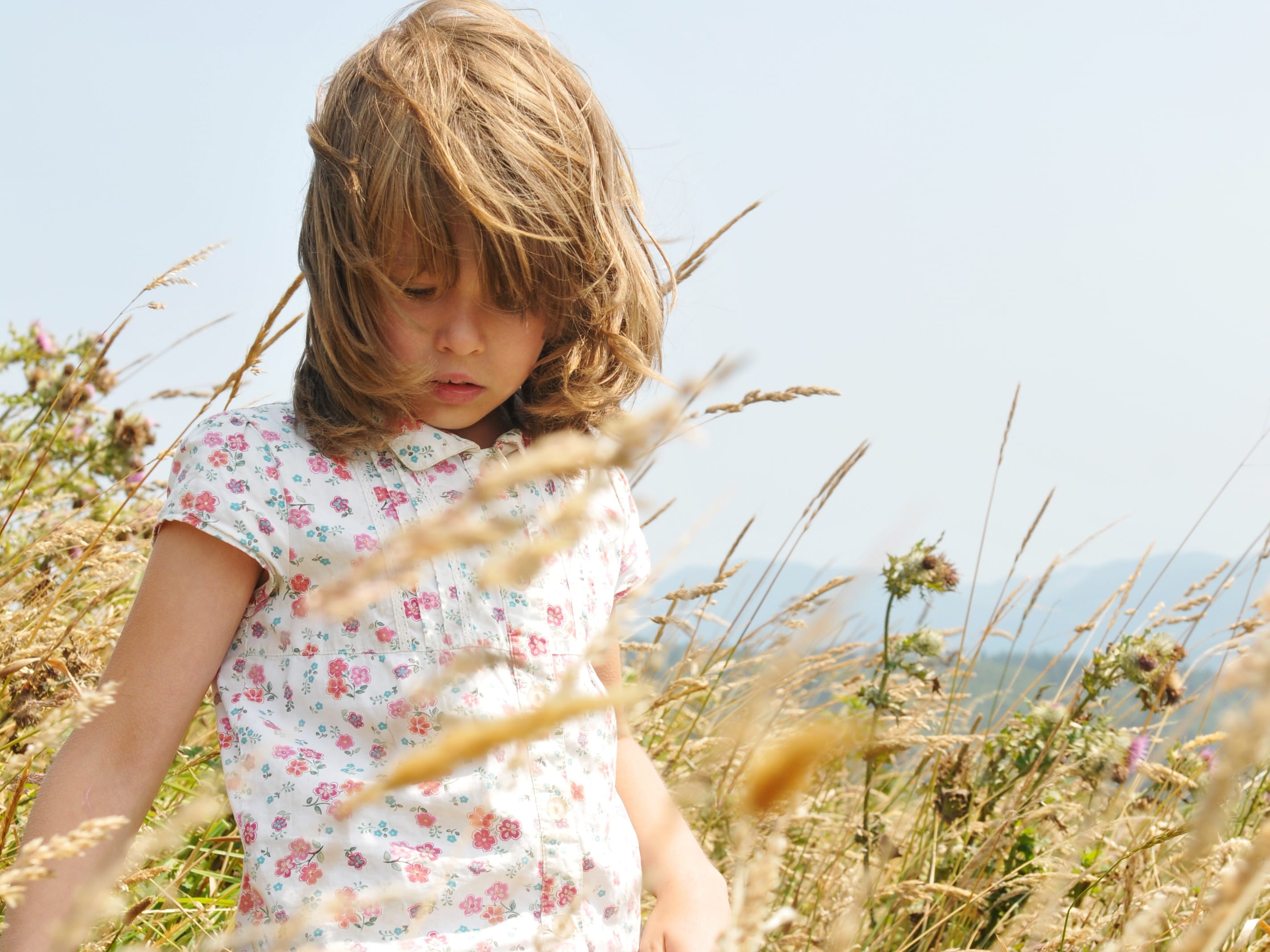 young girl walking in tall foxtail grass