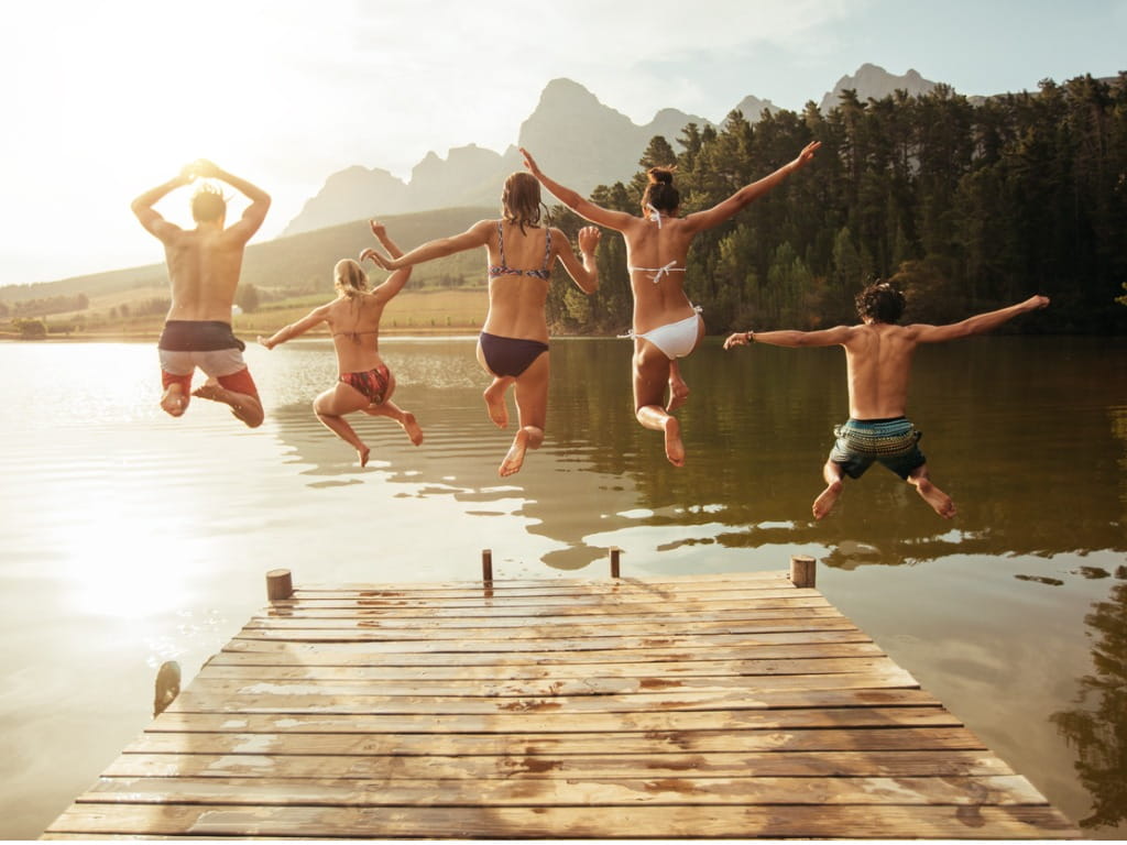 group jumping off a boardwalk into a lake