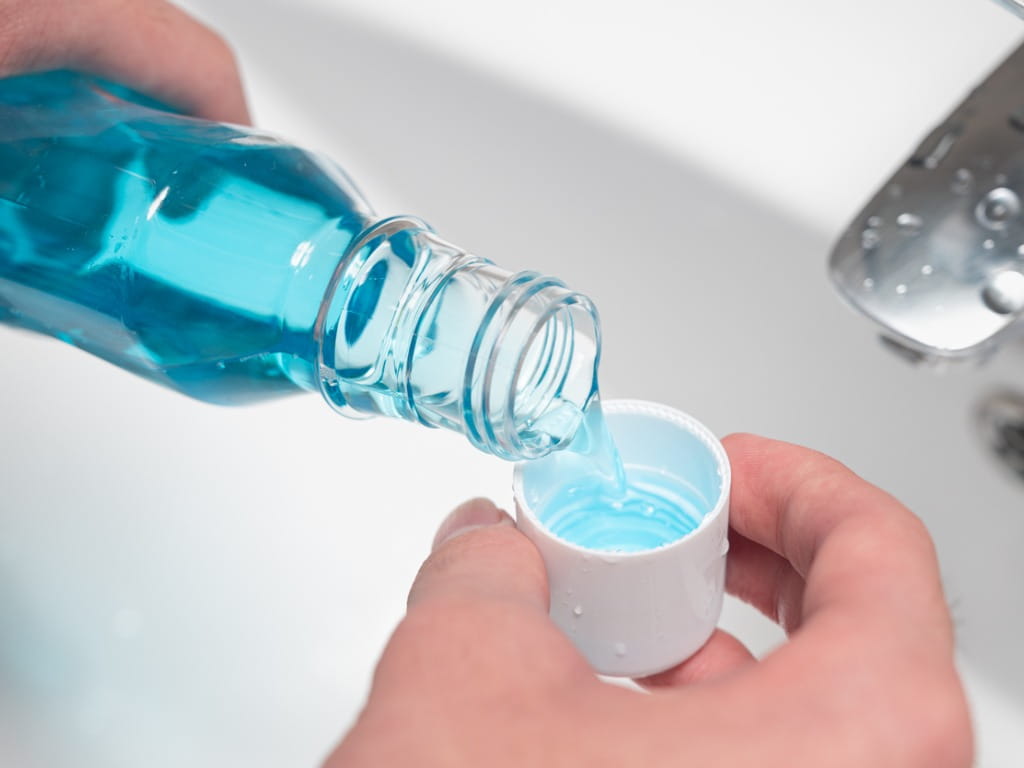 hands pouring mouthwash into its cap