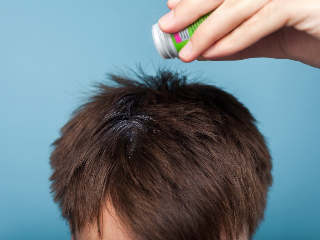 man applying dry shampoo powder