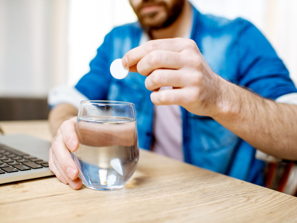 man dropping an aspirin pill into water