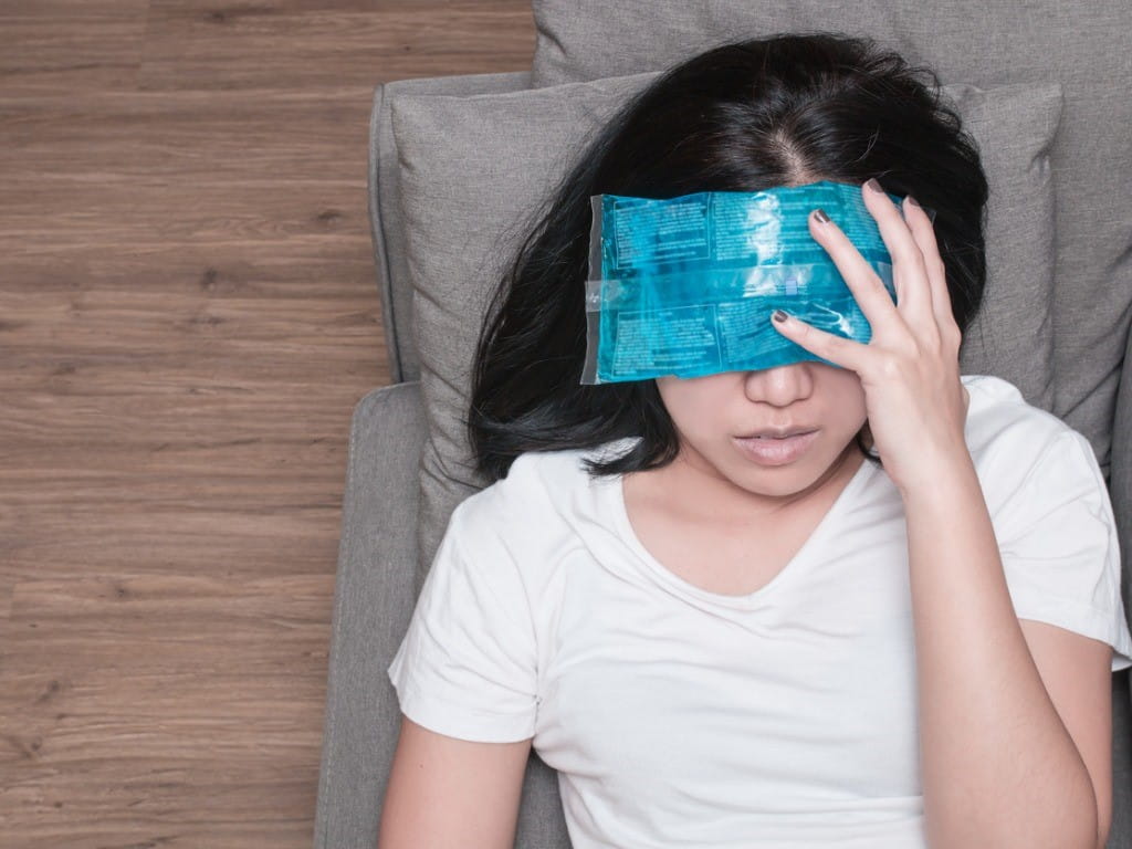 woman applying reusable ice pack to forehead and eyes