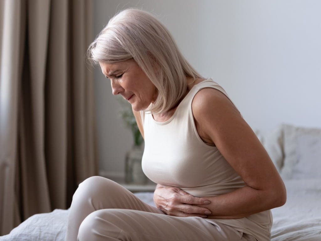 sick woman in white clutching her stomach