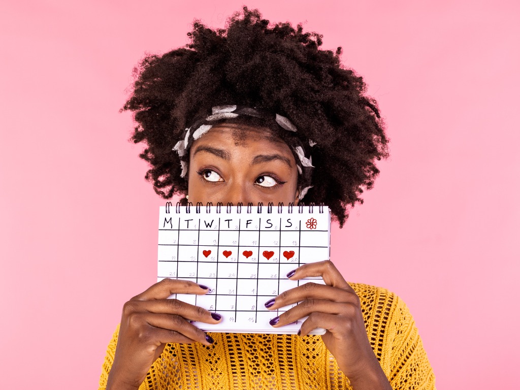 woman holding a calendar with a week marked with hearts