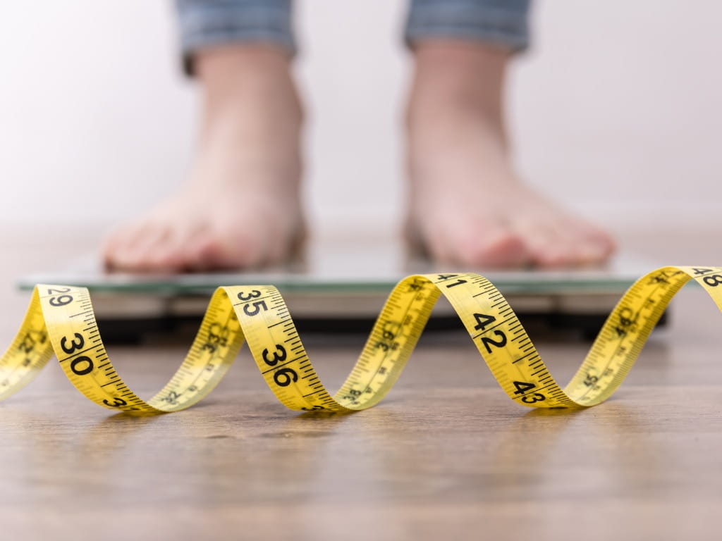 woman on scale with measuring tape