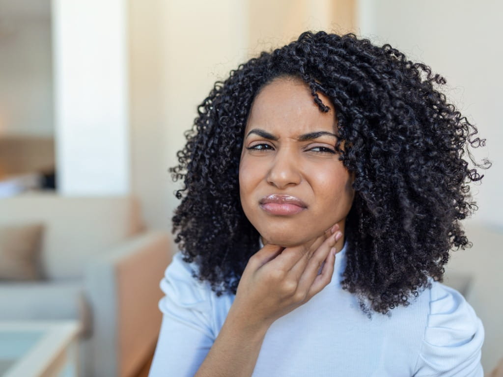 woman rubbing her neck and face due to swelling