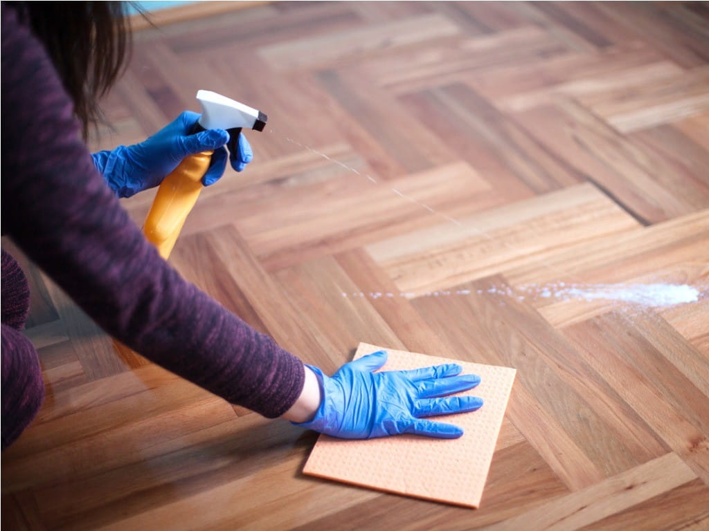 woman spraying floor cleaners on wood floor 