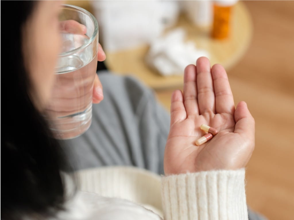 over the shoulder photo of a woman taking medication