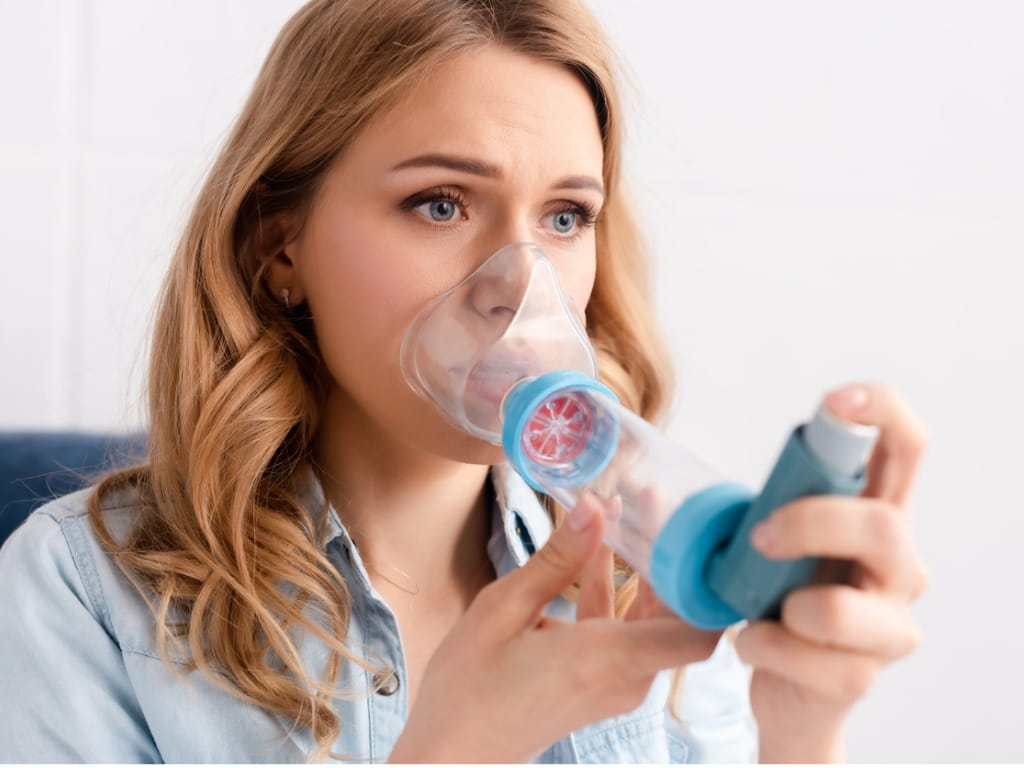 woman using an inhaler with a spacer