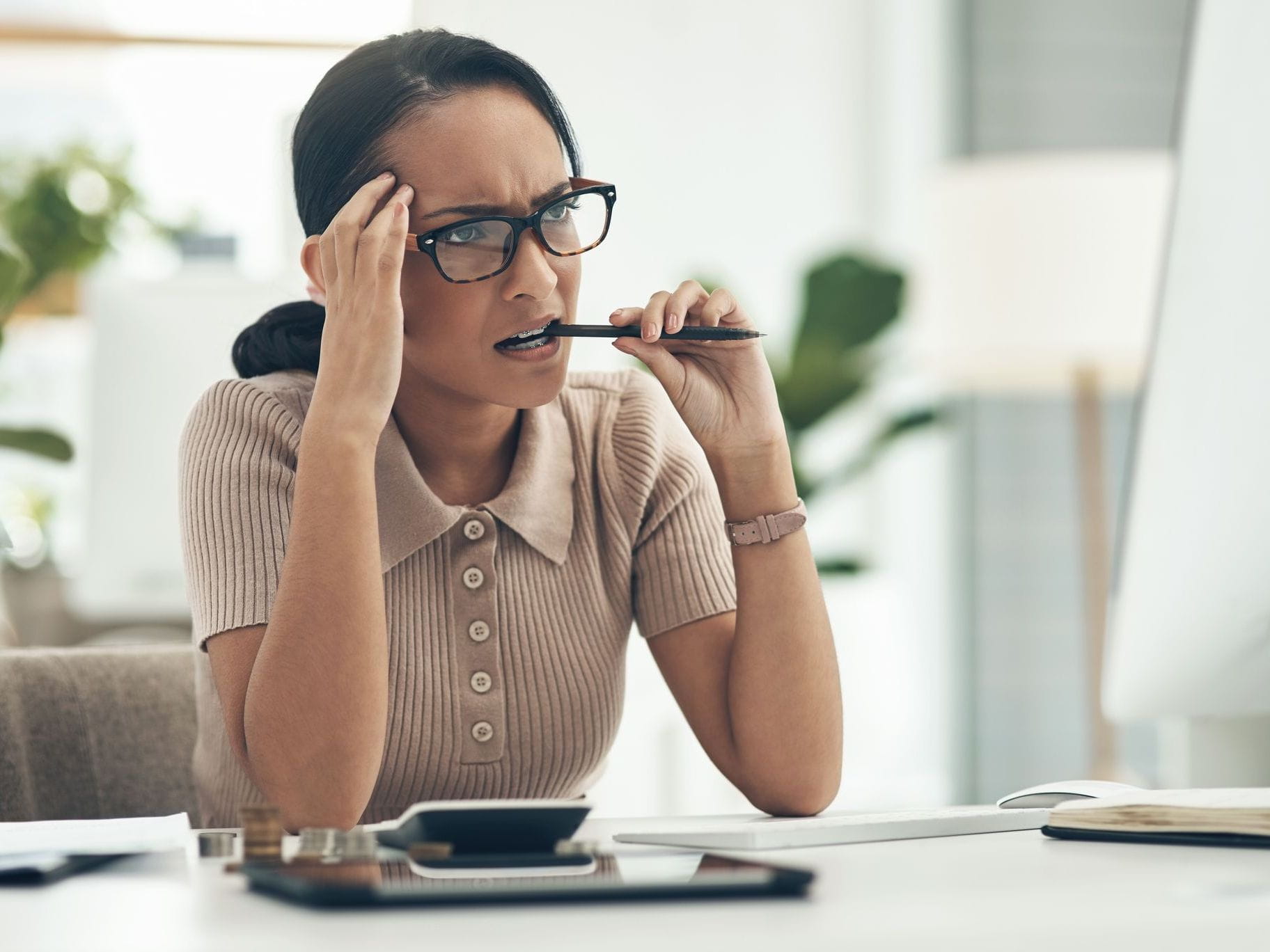 woman thinking while chewing on pen