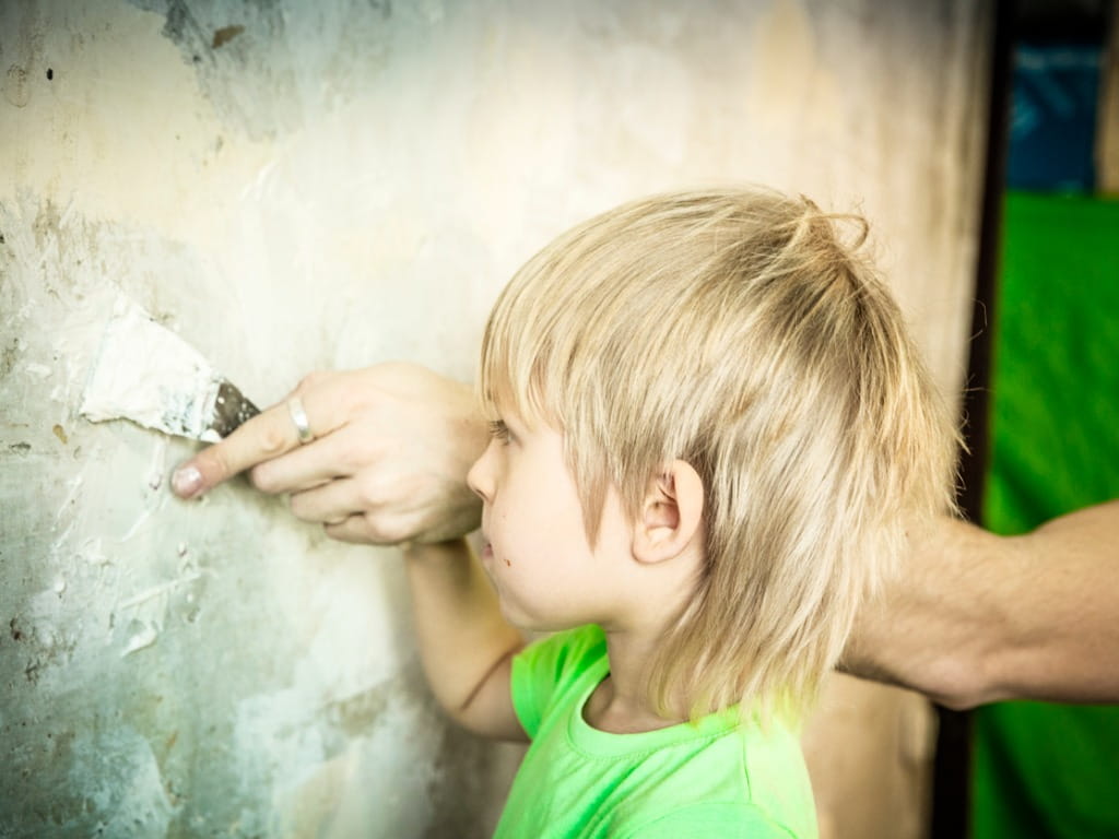 boy applying plaster spackle to the wall