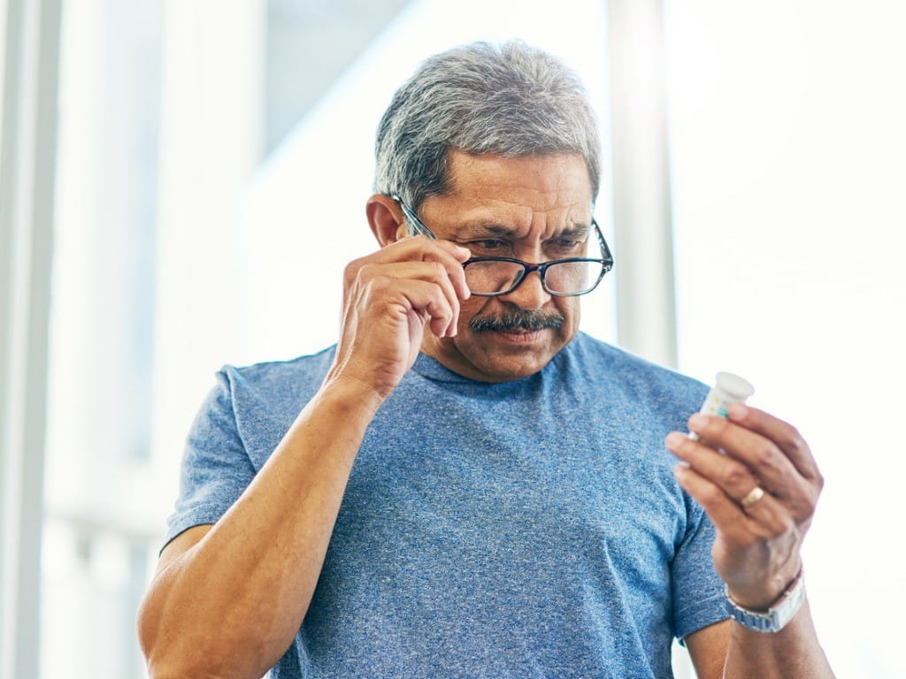 opioid epidemic history man carefully reading medication label