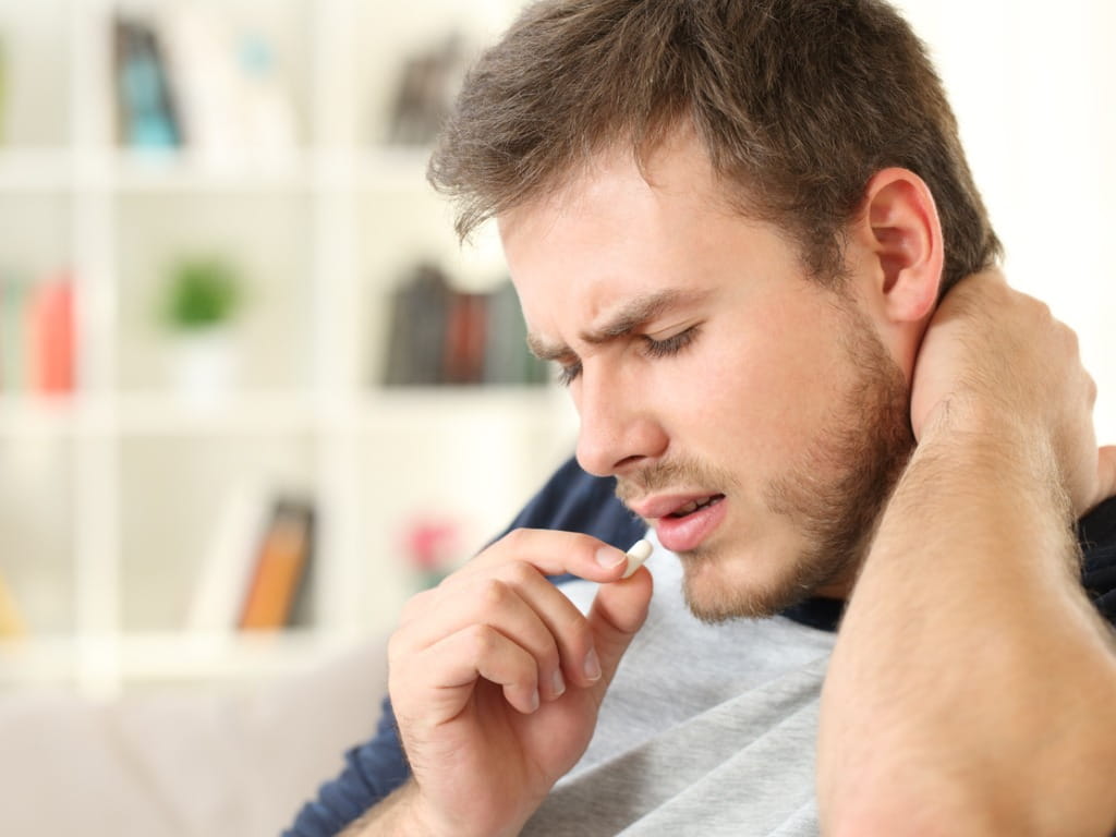 man with neck pain taking medicine