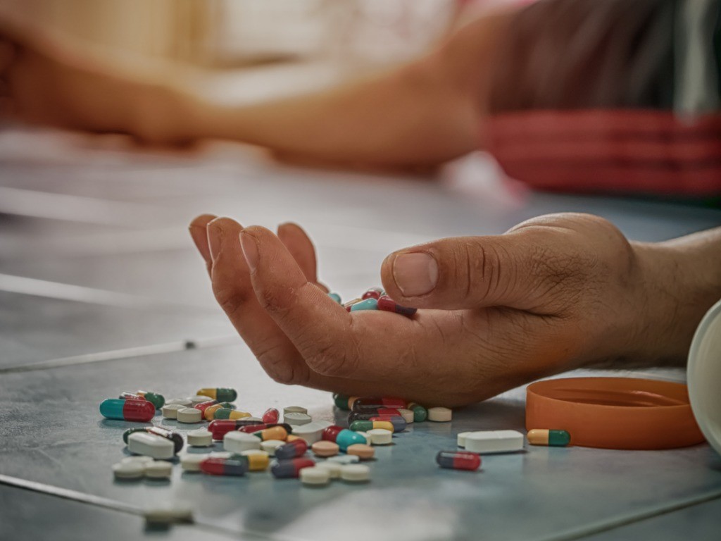 treating and preventing opoid overdose victim's hand and pills on floor